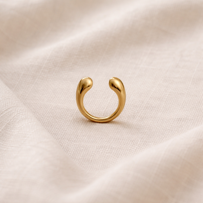 Gold ear cuff on a beige fabric background