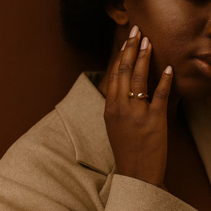 Close-up of a person wearing a gold ring with a brown background