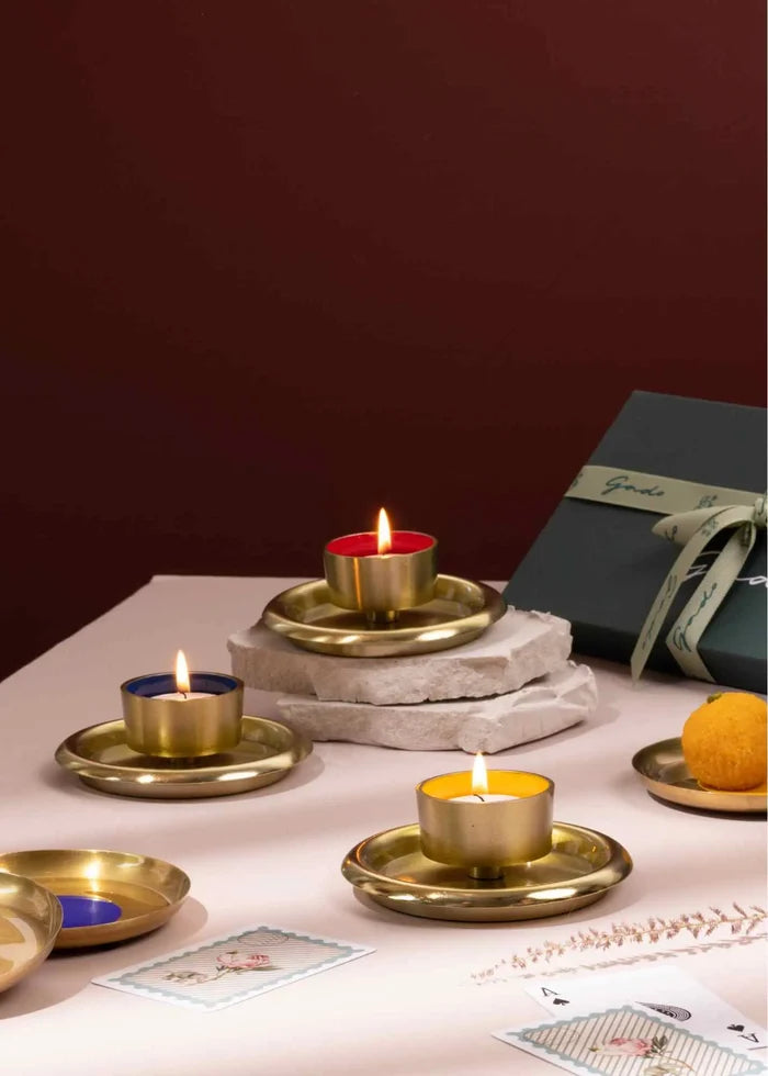 Decorative candles in brass holders on a table with a dark background
