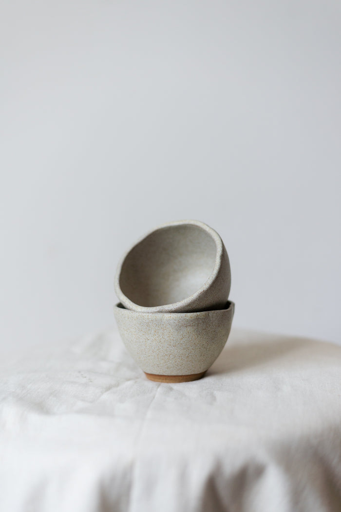 Minimalistisk håndlaget dessertskål i hvitt stentøy med en glatt, matt glasur.
