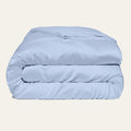 Light blue comforter folded on a beige background