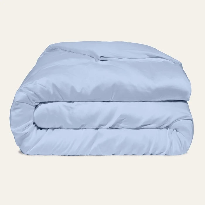 Light blue comforter folded on a beige background