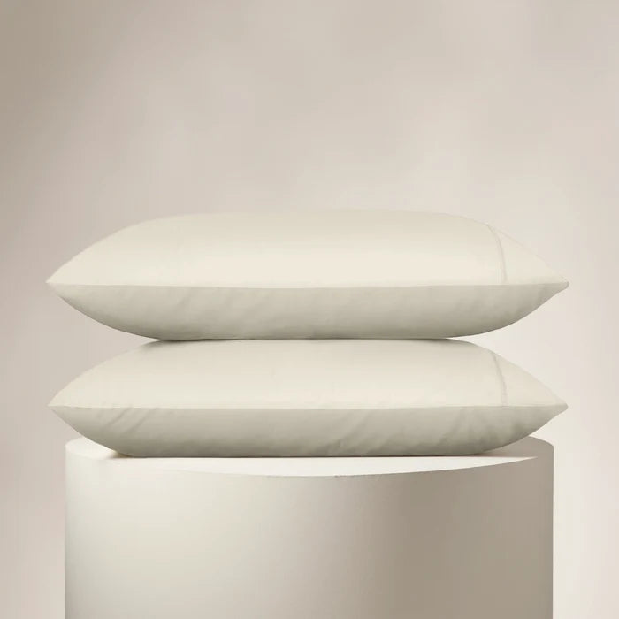 Two white pillows stacked on a light gray pedestal against a beige background