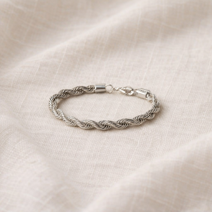 Silver braided bracelet on a beige fabric background