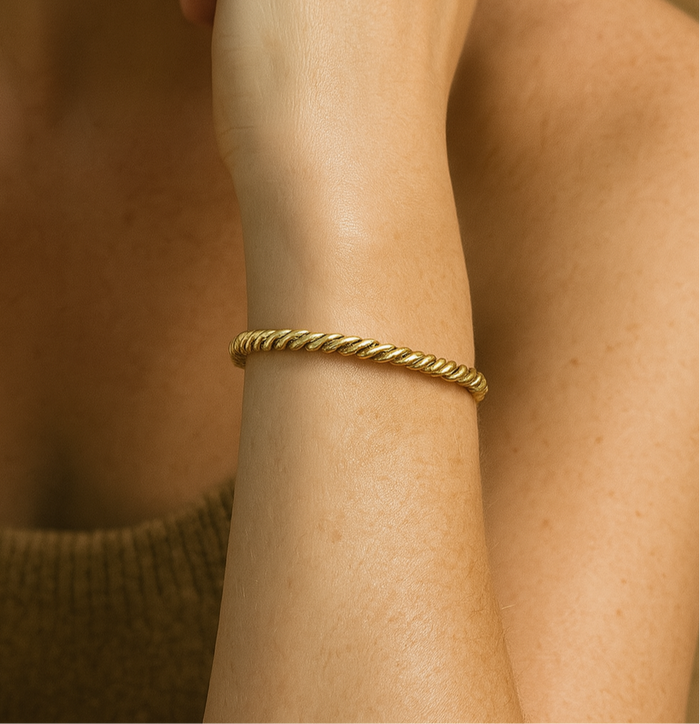 Model wearing the Keppa adjustable cuff, showing the texture and movement of the twisted brass on the wrist.