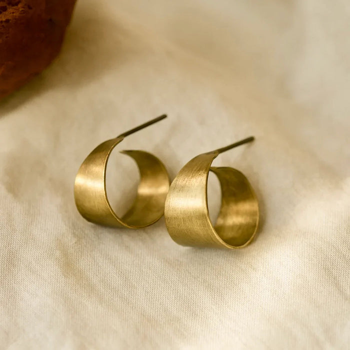 Pair of gold hoop earrings on a beige fabric background