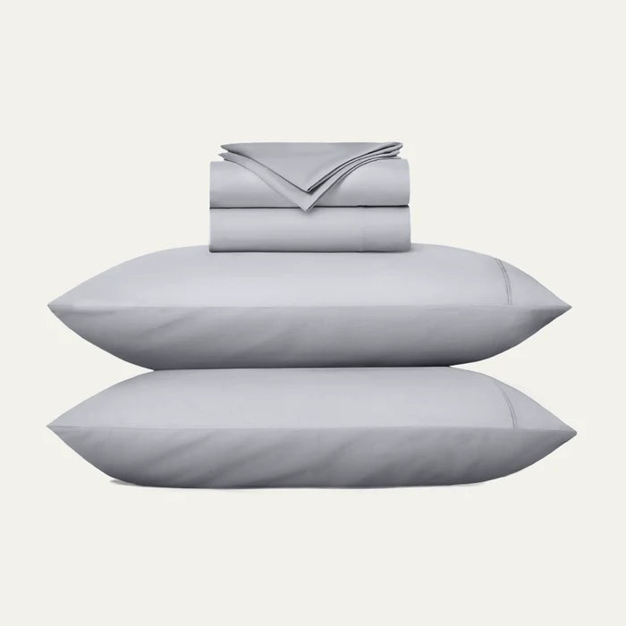 Gray bedding set with two pillows and a folded sheet on a white background