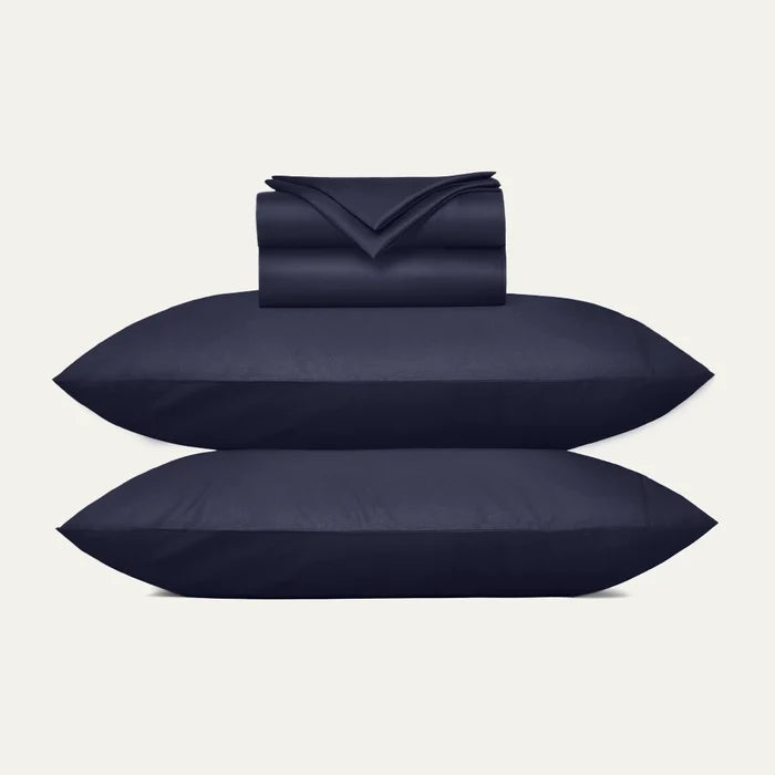 Navy blue bedding set including duvet, two pillows, and a folded blanket on a light gray background