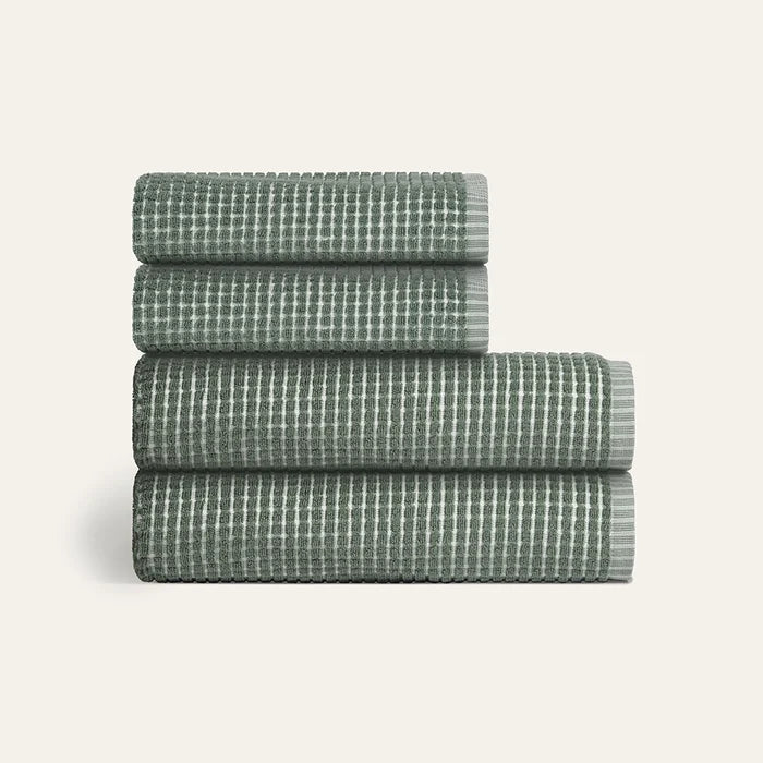 Stack of four folded green checkered towels on a light gray background