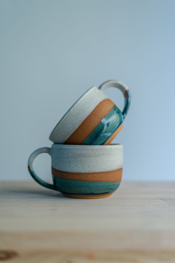 Handcrafted round stoneware cup with a smooth organic shape, perfect for holding warm coffee or tea.