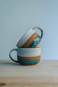 Handcrafted round stoneware cup with a smooth organic shape, perfect for holding warm coffee or tea.