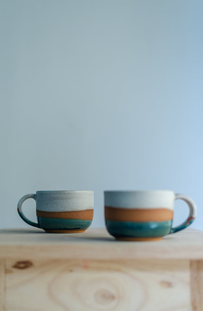 Handcrafted round stoneware cup with a smooth organic shape, perfect for holding warm coffee or tea.