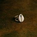 Silver ring with a shell design on a dark brown textured surface