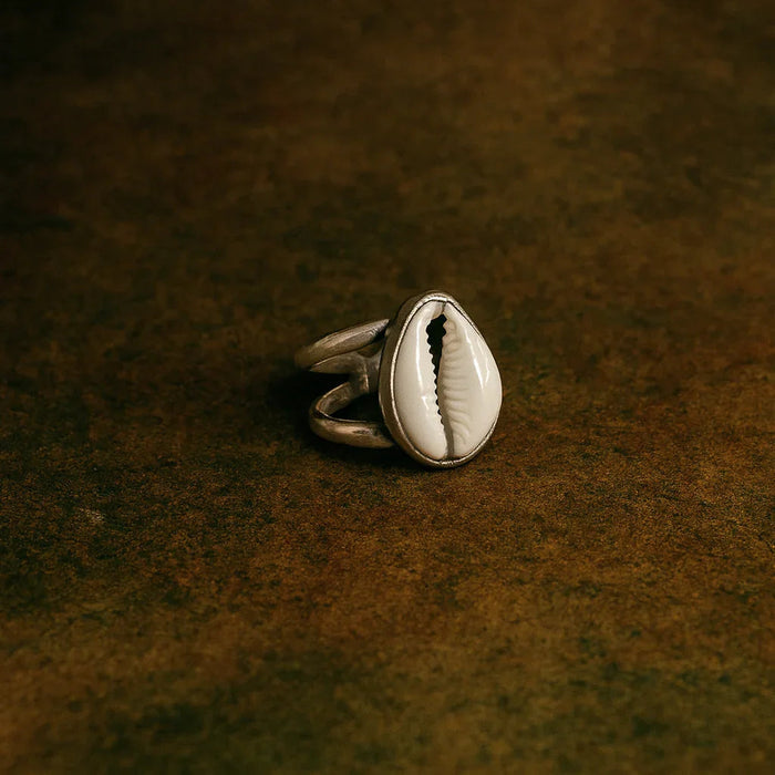 Silver ring with a shell design on a dark brown textured surface