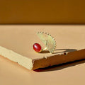 The Tano statement ring by Oriaku Studio, featuring a deep red natural stone set in handcrafted brass.