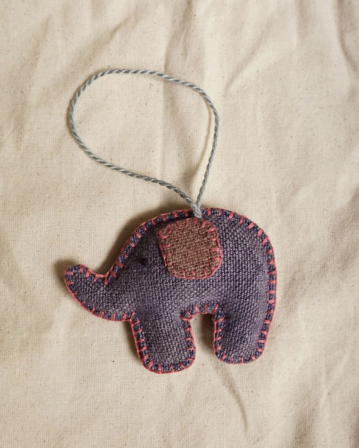 Handmade elephant ornament with a string on a beige fabric background